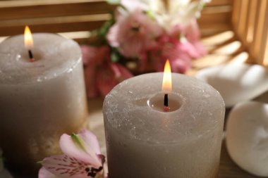 Yanan mumlar, taşlar ve nilüfer çiçekleri masada, yakın plan