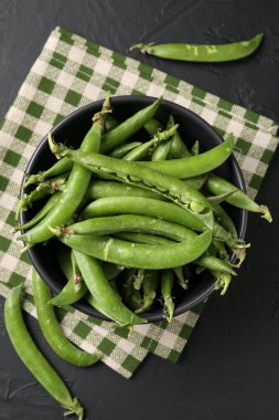 Taze taze bezelyeler siyah masada, düz yatıyordu.