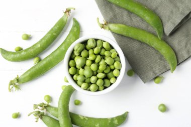 Taze taze bezelyeler beyaz ahşap masada, düz yatıyordu.