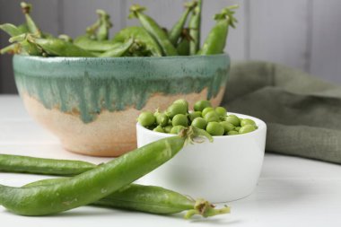 Taze taze bezelyeler beyaz ahşap masada, yakın plan.