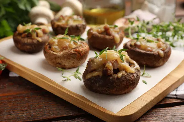 Eritilmiş peynirli lezzetli mantarlar ve ahşap masadaki kekik, yakın plan.