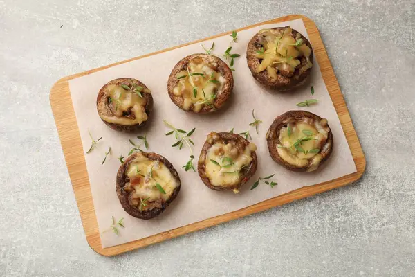 Eritilmiş peynirli lezzetli mantarlar ve gri desenli masa üzerinde kekik.