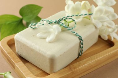 Açık kahverengi arka planda sabun ve yasemin çiçekleri, yakın plan.