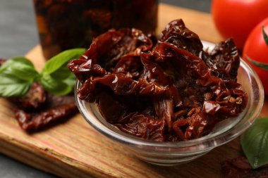 Lezzetli güneşte kurutulmuş domatesler ve taze sebzeler siyah masada, yakın plan.