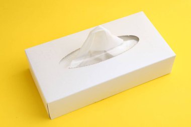 Sarı arka planda kağıt mendilli kutu, yakın plan.