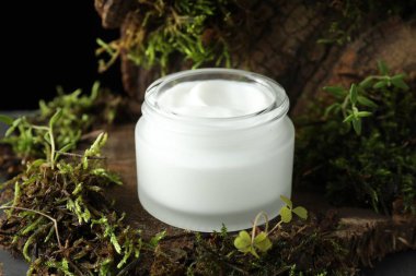 Ağaç kabuğunda bitkilerle birlikte nemlendirici vücut kremi, yakın plan.