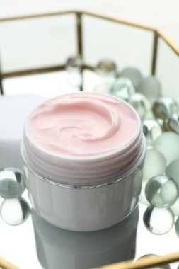 Beyaz masadaki nemlendirici krem ve cam tepsi, yakın plan.