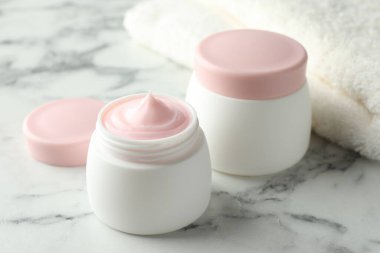 Beyaz mermer masanın üzerinde bir kavanoz nemlendirici vücut kremi, yakın plan.