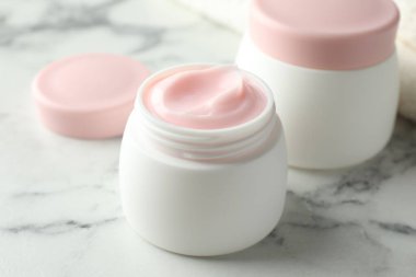 Beyaz mermer masanın üzerinde bir kavanoz nemlendirici vücut kremi, yakın plan.