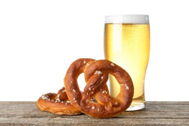 Lezzetli krakerler ve beyaz arka plana karşı ahşap masada bir bardak bira.