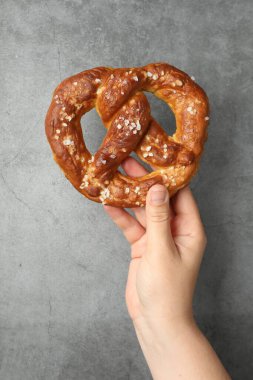 Gri desenli duvarın yanında lezzetli krakerli kadın, yakın plan.