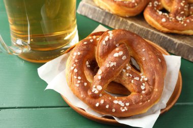 Lezzetli krakerler ve yeşil ahşap masada bir bardak bira, yakın plan.