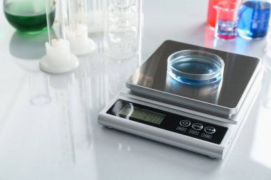 Beyaz ayna masasındaki Petri kabı ve diğer laboratuvar camlarıyla ölçeklendir, yakın plan.