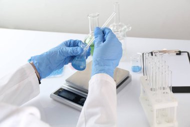 Beyaz masada numune ve ölçeklerle çalışan bilim adamı, yakın plan.