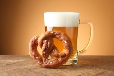 Lezzetli kraker ve cam bardak bira ahşap masada bej renkli arka planda, yakın plan