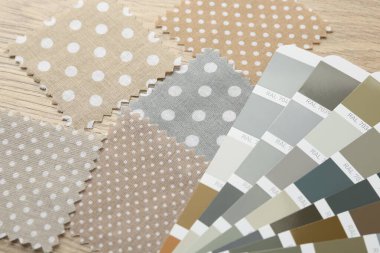 Ahşap masada renkli kumaş örnekleri ve renk paletleri, yakın plan.