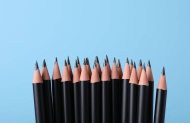 Açık mavi arka planda birçok keskin grafit kalem, yakın plan. Metin için boşluk