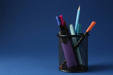 Koyu mavi arka planda kalem tutacağında farklı bir kırtasiye malzemesi. Metin için boşluk