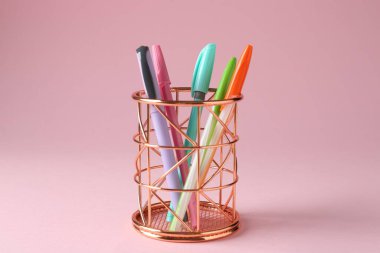 Pembe arka planda kalem tutacağında farklı bir kırtasiye