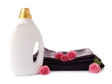 Bir şişe yumuşatıcı, üst üste yığılmış giysiler ve beyaza saklanmış çiçekler.