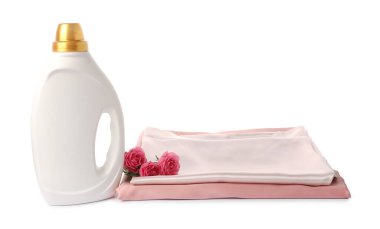 Bir şişe yumuşatıcı, üst üste yığılmış giysiler ve beyaza saklanmış çiçekler.
