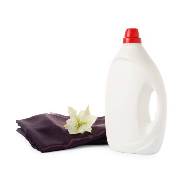 Bir şişe yumuşatıcı, üst üste yığılmış giysiler ve beyaz bir çiçek.