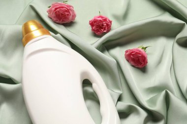 Bir şişe yumuşatıcı ve yeşil kumaş üzerinde çiçekler.