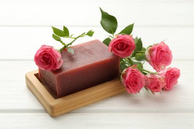 Sabun barı ve beyaz ahşap masada güzel güller, yakın plan.