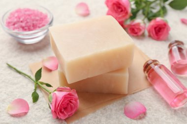 Sabun çubukları, deniz tuzu, temel yağlar ve bej masadaki güzel güller, yakın plan.