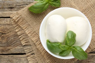 Ahşap masada lezzetli mozzarella peyniri ve fesleğen.