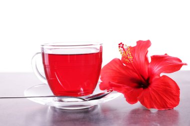 Lezzetli amber çayı fincanda, kaşık ve güzel çiçek gri desenli masada beyaz arka planda.