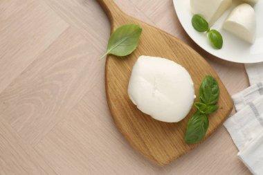 Ahşap masada mozzarella peyniri ve fesleğen var. Metin için boşluk