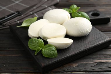 Nefis mozzarella peyniri ve fesleğen parçaları ahşap masada, yakın plan.