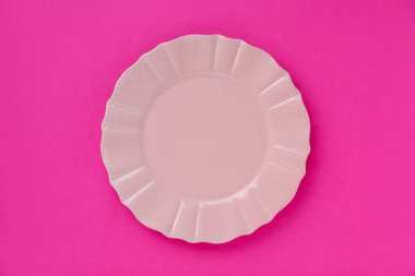 Pembe arka planda boş bir tabak, üst görünüm