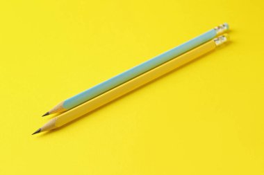 Sarı zemin üzerinde iki grafit kalem, üst görünümde.