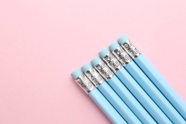 Pembe arka planda silgileri olan çizgili kalemler. Metin için boşluk