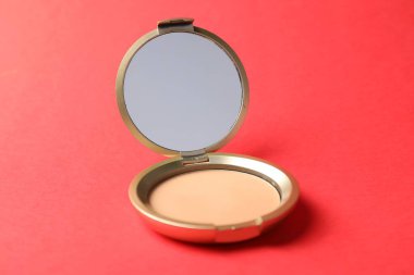 Kırmızı arkaplanda aynalı açık yüz pudrası, yakın plan