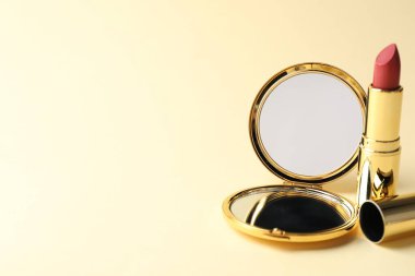 Bej arka planda cep aynası ve ruj izi, yakın plan. Metin için boşluk