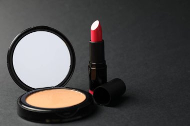 Aynalı açık yüz pudrası ve siyah arka planda ruj, yakın plan. Metin için boşluk