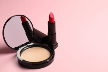 Aynalı açık yüz pudrası ve pembe arka planda ruj, yakın plan. Metin için boşluk
