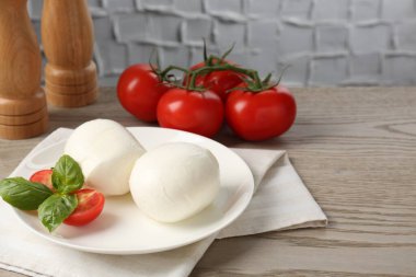 Lezzetli mozzarella peyniri topları, domates ve fesleğen, ahşap masa, yakın plan. Metin için boşluk