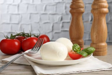 Lezzetli mozzarella peynir topları, domates ve fesleğen ahşap masada, yakın plan.