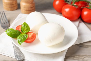 Lezzetli mozzarella peynir topları, domates ve fesleğen ahşap masada, yakın plan.