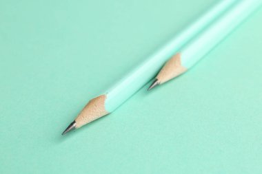 Turkuaz arka planda iki grafit kalem, yakın plan.