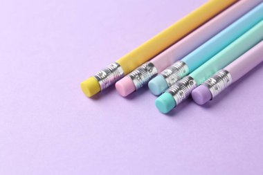 Menekşe arka planında silgi olan birçok grafit kalem, yakın plan. Metin için boşluk