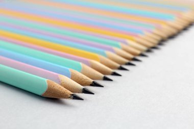 Açık gri arka planda birçok grafit kalem, yakın plan. Metin için boşluk