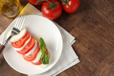 Lezzetli mozzarella, domates, ahşap masada yağ ve fesleğen, düz yatak. Metin için boşluk