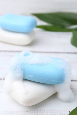 Köpüklü sabun çubukları beyaz ahşap masa, yakın plan.