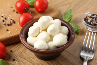 Lezzetli mozarella topları, domatesler, biberler ve fesleğenler ahşap masada, yakın plan.