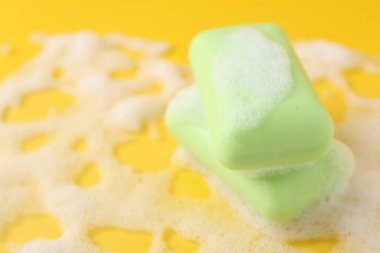 Sarı arka planda köpüklü sabun çubukları, yakın plan. Metin için boşluk